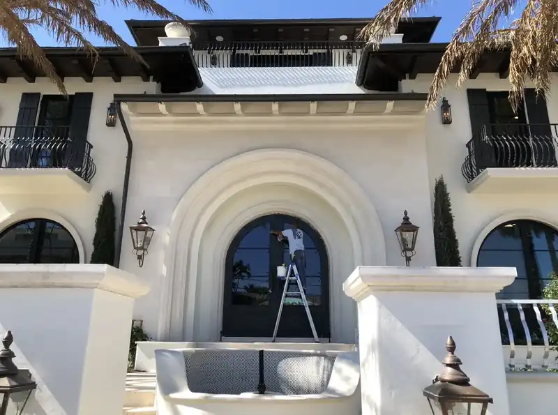 Newly completed Mediterranean-style custom home in Fort Lauderdale with a carved stone arched entry and copper lanterns